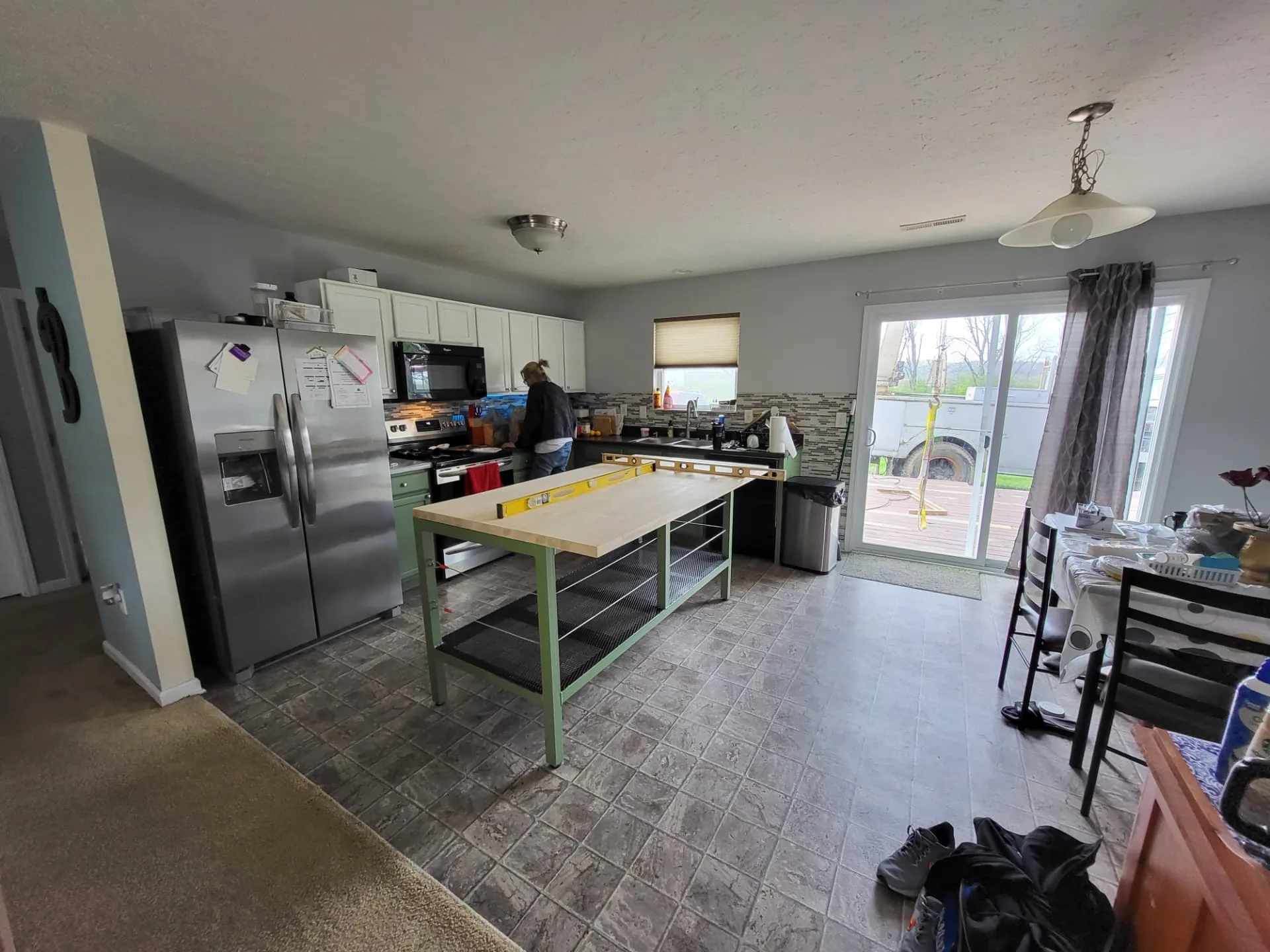 Wide view of the open kitchen and dining area with the completed CinStar island and the crane truck visible outside the sliding door