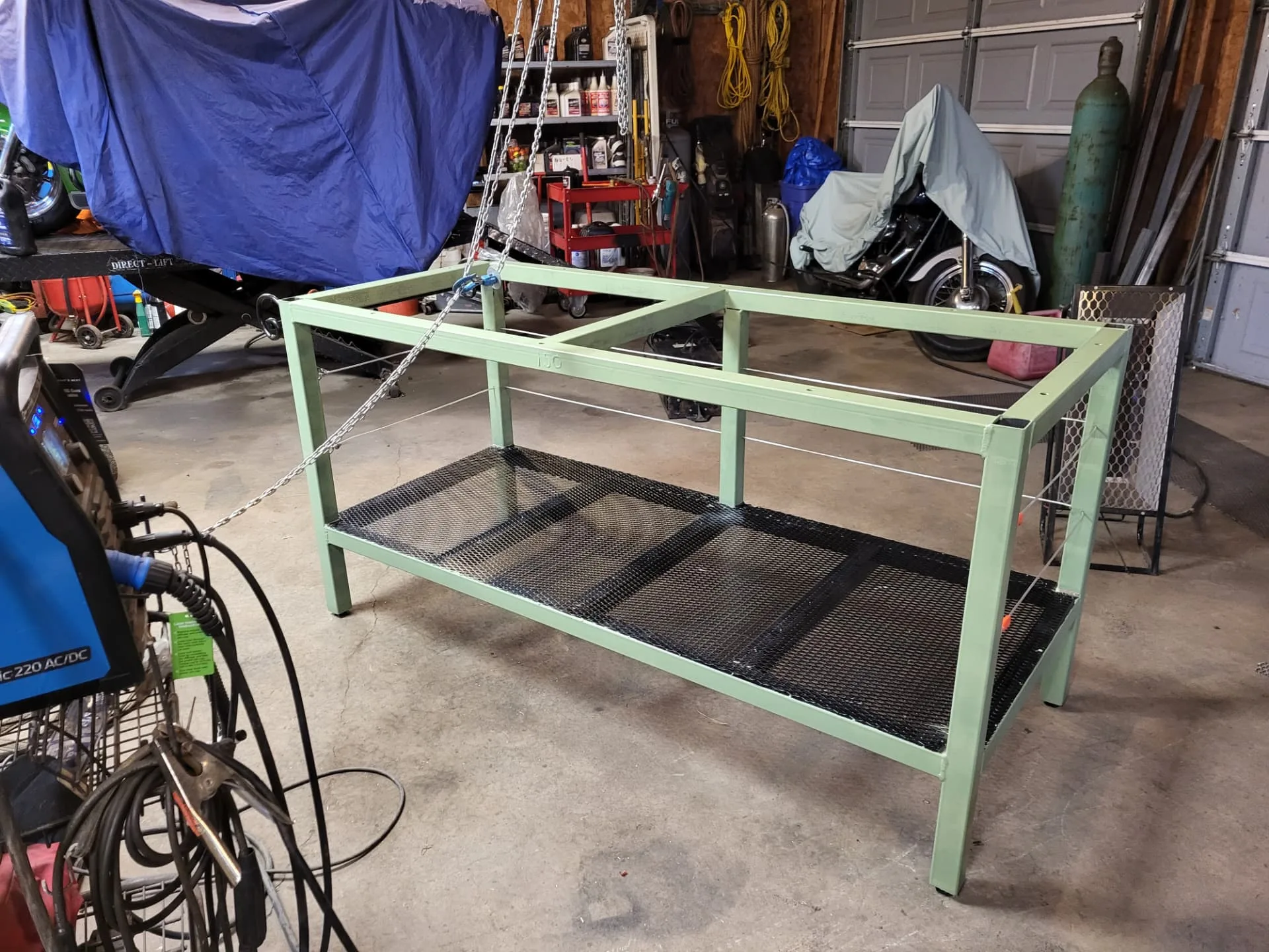 Kitchen island base painted in sage green with expanded metal shelves, built by CinStar